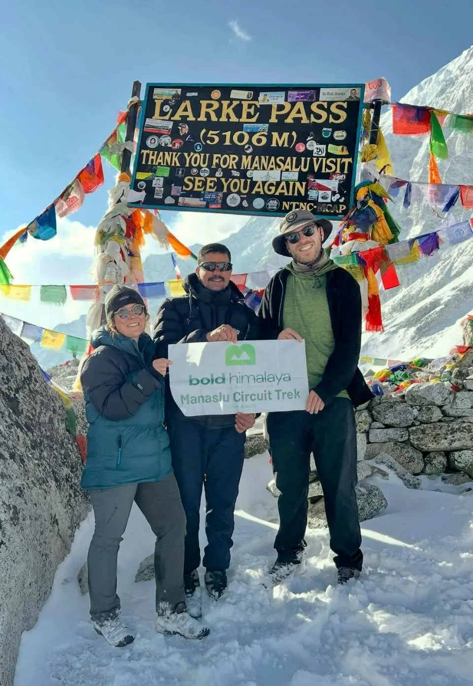 ทีมเดินป่า Bold Himalaya กำลังเฉลิมฉลองความสำเร็จบนยอดเขา Larkya La Pass (5,106 เมตร) ซึ่งเป็นจุดที่สูงที่สุดและท้าทายที่สุดของการเดินป่าเส้นทาง Manaslu Circuit Trek ท่ามกลางเทือกเขาหิมาลัยอันยิ่งใหญ่ที่ปกคลุมไปด้วยหิมะ เช่น เทือกเขา Himlung Himal, Cheo Himal และเทือกเขา Annapurna II ทีมงานยืนอย่างภาคภูมิใจท่ามกลางทัศนียภาพอันกว้างใหญ่ของเทือกเขาแอลป์ที่ก่อร่างสร้างโดยธารน้ำแข็ง ลมหนาว และภูมิประเทศที่เป็นหินกรวดขรุขระ