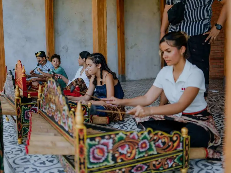 A focused participant at a Bali Rindik Gamelan music workshop learns to play traditional bamboo instruments, immersed in the island's unique harmonies.
