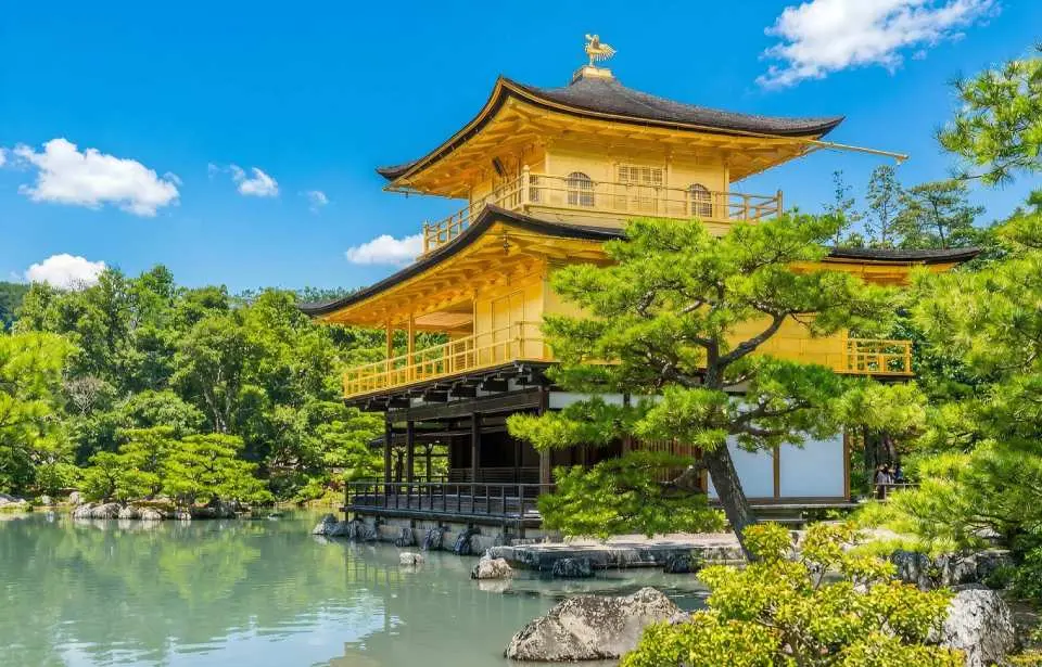 Kinkaku-ji Temple, with its exterior walls gleaming with gold leaf, is reflected in the Mirror Pond, creating a breathtaking scene.