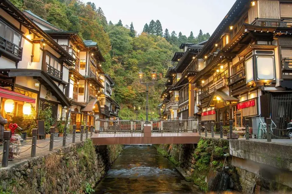 銀山溫泉：抵達後將轉乘接駁小巴前往銀山溫泉入口，步行約2–3分鐘即可進入溫泉街。銀山溫泉以大正浪漫風情聞名，兩旁林立百年木造旅館，其中最具代表性的能登屋旅館更被視為宛如動漫場景般的經典地標。漫步於溫泉河道、小橋與復古街燈之間，感受濃厚懷舊氛圍，也因此被許多旅客認為是最接近《千與千尋》世界觀的溫泉街之一。自由活動期間可拍攝美景、品嚐特色甜點與咖啡、體驗足湯，或選購山形特色伴手禮，享受悠閒的溫泉街時光。