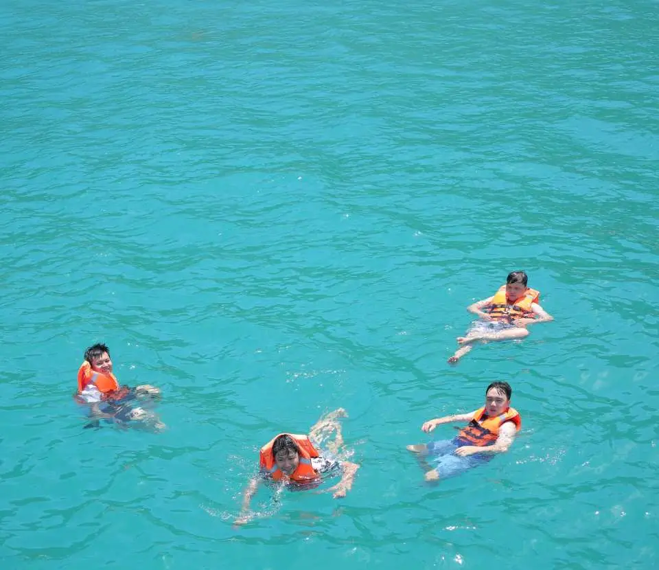 数名旅客穿着救生衣，在芽庄宁凡湾晶莹剔透的海水中尽情游泳与浮潜。