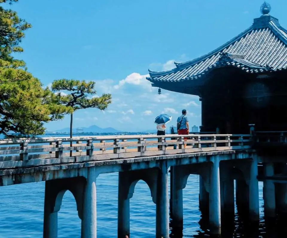 位于琵琶湖西岸的满月寺浮御堂，是一座仿佛漂浮在湖面上的古老佛堂。相传建于平安时代，由高僧源信为祈愿湖上安全与众生安宁而建。木质回廊延伸至湖中，尽头的佛堂静静伫立，与湖水与远山融为一体，营造出极具禅意的宁静氛围。