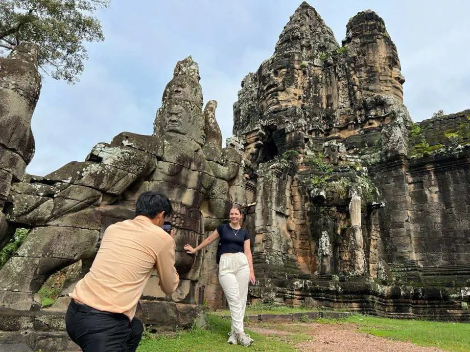 Stop and capture a photo at the West Gate of Angkor Thom captures the excitement and adventurous spirit of exploring Cambodia’s ancient wonders. The bright midday sunlight and clear blue skies create perfect conditions for memorable photos while visiting one of the most impressive entrances to the Khmer Empire’s last royal city.