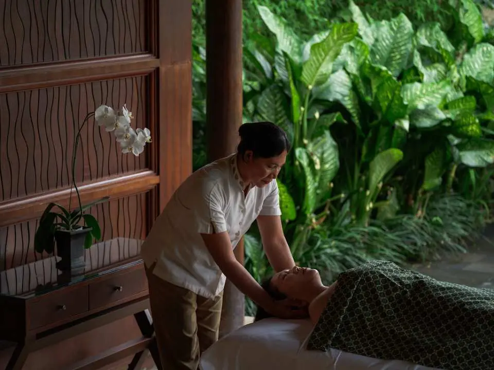 알릴라 우붓 스파의 전문 테라피스트가 고객에게 부드러운 헤드 마사지를 제공하여 발리 전통 치료의 정수와 정성을 보여줍니다.