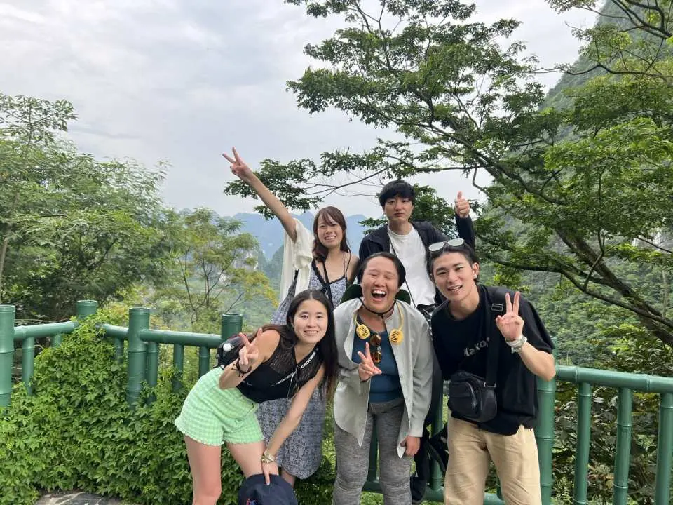 A group of young friends posing happily outdoors in Northern Vietnam, smiling and gesturing, enjoying their time exploring nature on this small group tour.