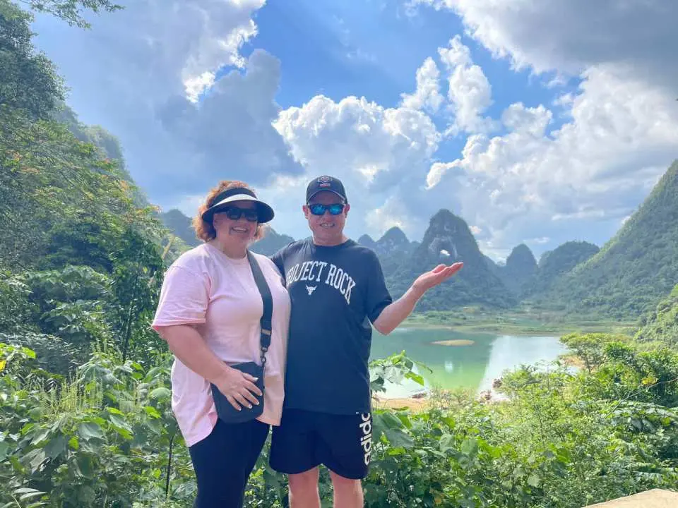 ベトナム北部の高地にある息をのむようなパノラマビューを眺めるカップル。雄大なカルスト地形と穏やかなエメラルドグリーンの湖が広がり、エンジェルマウンテンの少人数ツアーのハイライト。