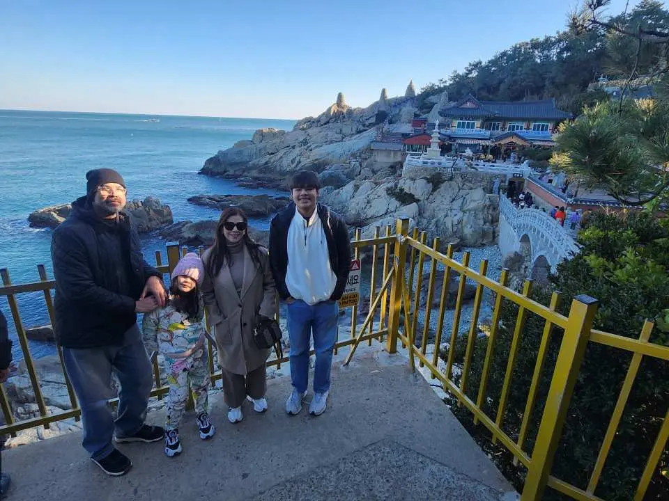 一群朋友在釜山一日遊中，於海東龍宮寺附近沿海步道欣賞壯麗海景，享受悠閒時光。