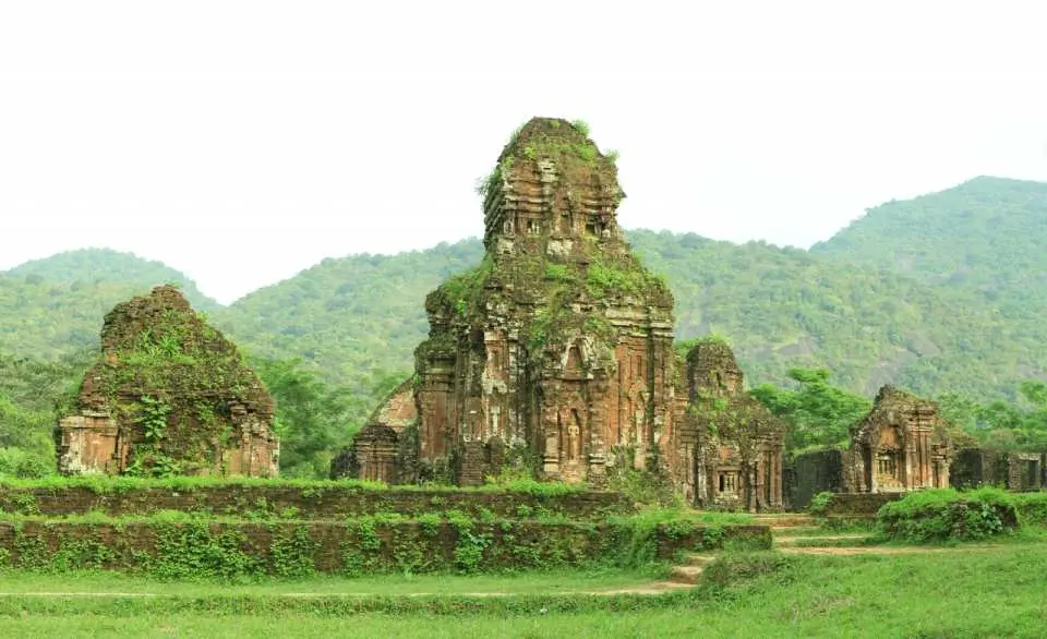 廣闊的美山聖地遺址全景，古老磚塔點綴綠意，背景是層疊的青翠山丘，探索峴港附近的聯合國教科文組織景點。