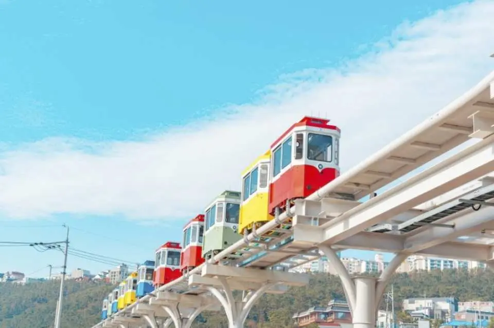 The Coast Sky Capsule Train is a popular attraction on the Busan Haeundae Blue Line, converted from the old Donghae South Line. The train travels on an approximately 2-kilometer elevated track, with a maximum capacity of 4 passengers per car. The journey along the coast takes about 30 minutes, offering stunning views of Busan's mountains and sea from the colorful carriages.
