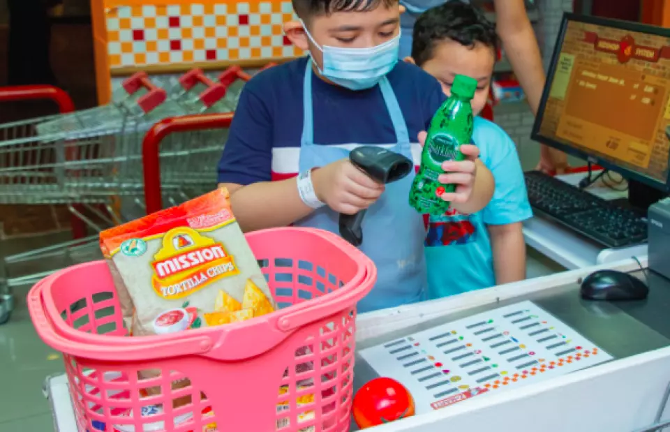 Child scanning a bottle of soda at a supermarket in KidZania Kuala Lumpur