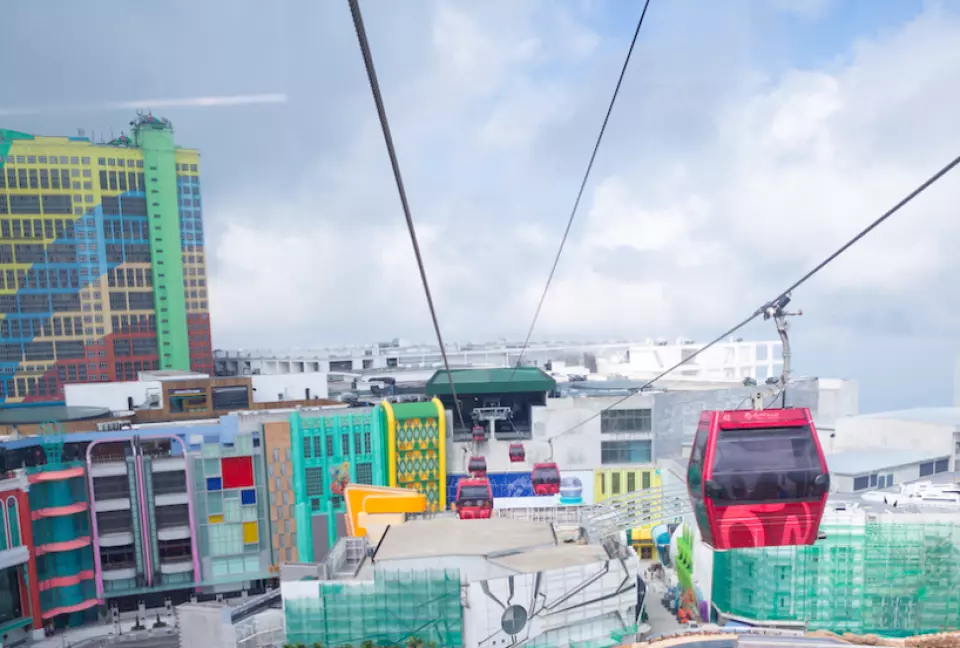 Multiple cable cars passing by colorful buildings at Awana SkyWay, Genting Highlands, Pahang